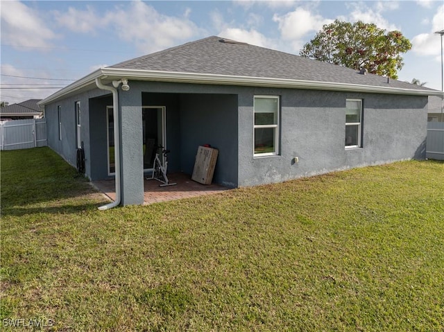 rear view of house featuring stucco siding, a yard, a patio, and fence