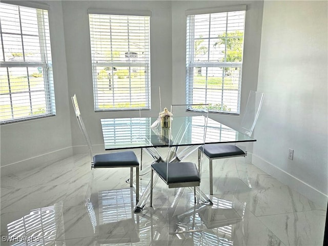 dining space with baseboards, marble finish floor, and a healthy amount of sunlight