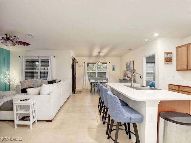 kitchen with visible vents, open floor plan, light countertops, a kitchen bar, and a sink