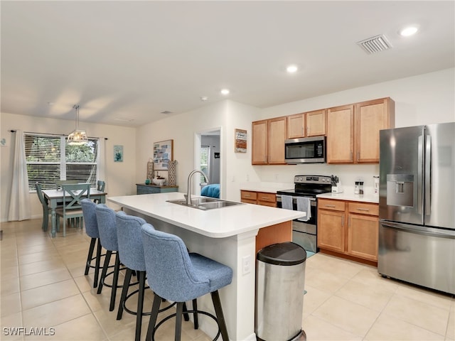 kitchen featuring visible vents, stainless steel appliances, light countertops, a kitchen bar, and a sink