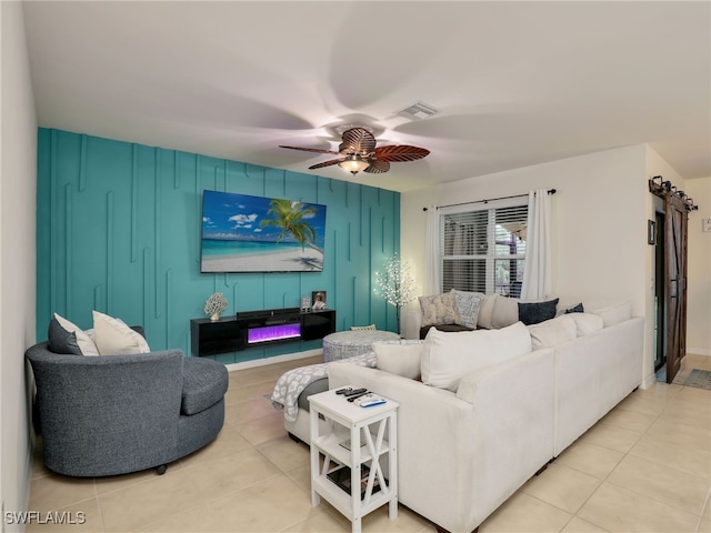 living area featuring an accent wall, visible vents, ceiling fan, and light tile patterned floors