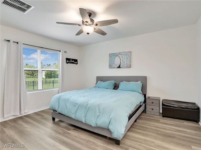 bedroom featuring a ceiling fan, baseboards, visible vents, and light wood finished floors