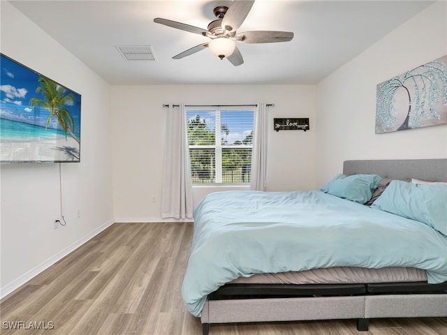 bedroom featuring a ceiling fan, visible vents, baseboards, and wood finished floors