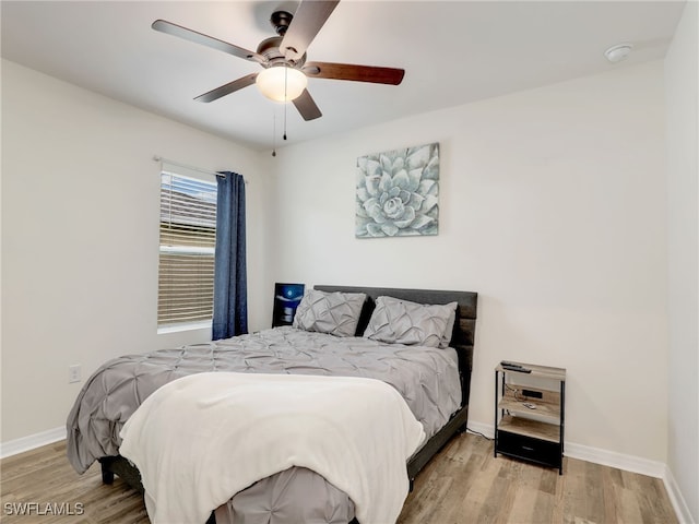 bedroom featuring a ceiling fan, baseboards, and wood finished floors