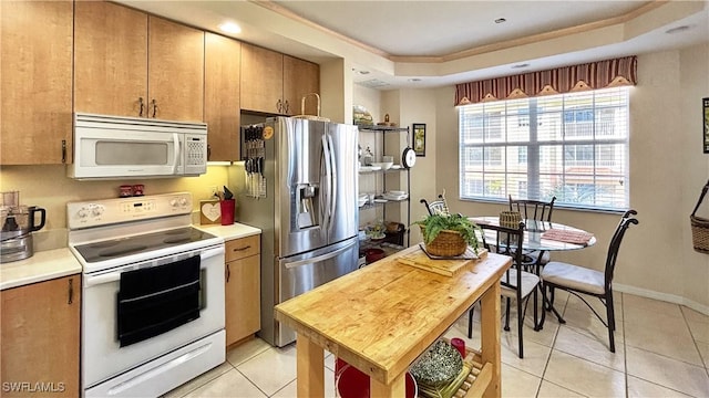 kitchen featuring light tile patterned floors, white appliances, baseboards, light countertops, and a tray ceiling