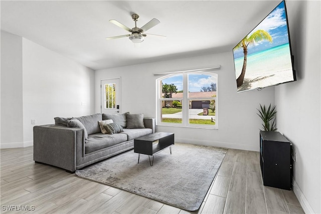 living room with a ceiling fan, baseboards, and wood finished floors