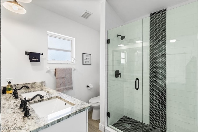 bathroom with double vanity, visible vents, toilet, a sink, and a shower stall