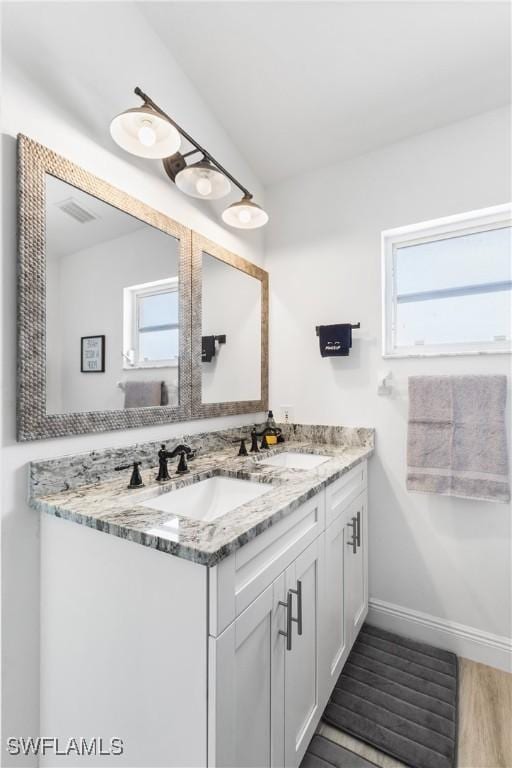 bathroom with double vanity, visible vents, a sink, and wood finished floors