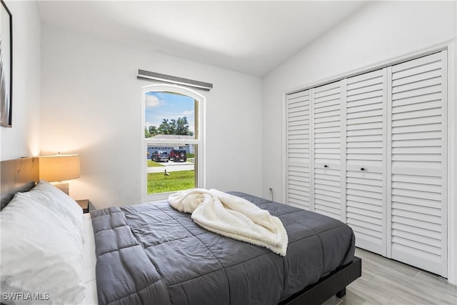 bedroom with vaulted ceiling, a closet, and light wood-style floors