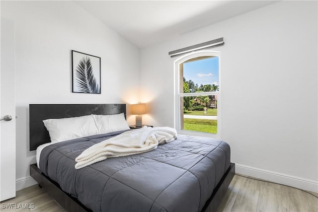 bedroom featuring lofted ceiling, wood finished floors, and baseboards