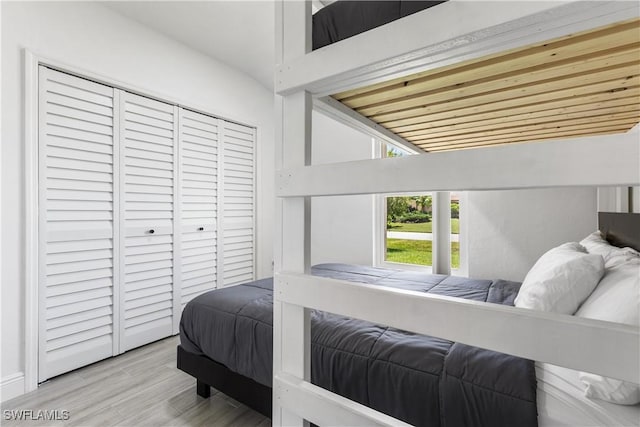 bedroom with lofted ceiling, a closet, and wood finished floors