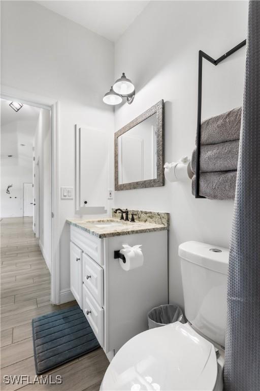 bathroom featuring toilet, wood finished floors, and vanity