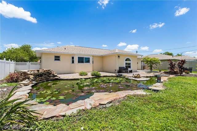 rear view of house featuring a patio, a fenced backyard, a garden pond, and stucco siding