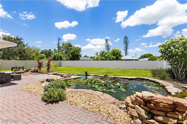 view of swimming pool featuring a patio area, a fenced backyard, and a small pond