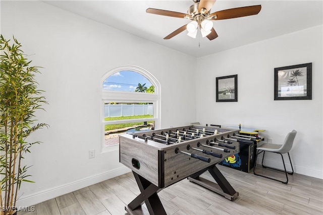 recreation room with light wood-type flooring, ceiling fan, and baseboards