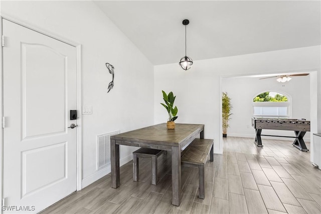 dining space with wood finish floors, visible vents, vaulted ceiling, and baseboards