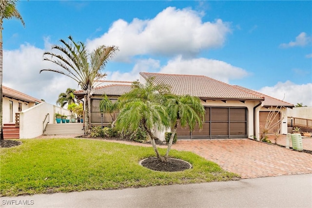 view of front facade with a garage, a tile roof, decorative driveway, a front lawn, and stucco siding