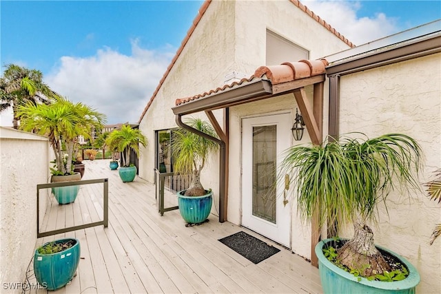 exterior space with a tile roof, a wooden deck, and stucco siding