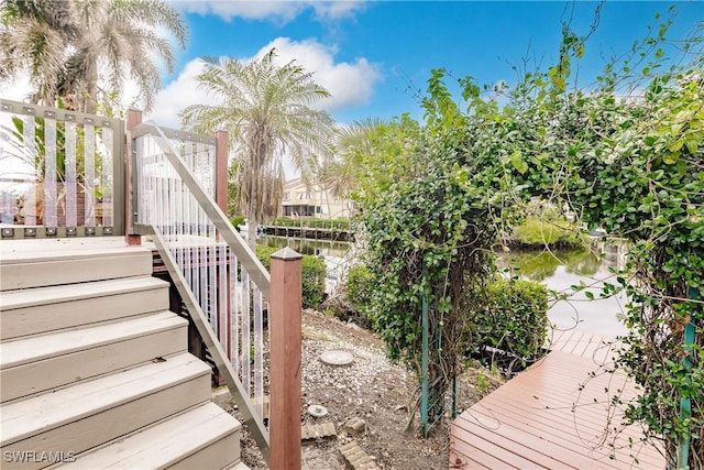 exterior space featuring stairway and a deck with water view