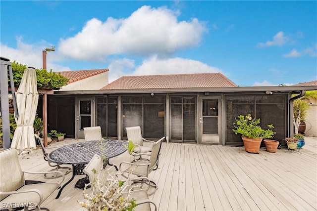 wooden terrace featuring outdoor dining area and a sunroom