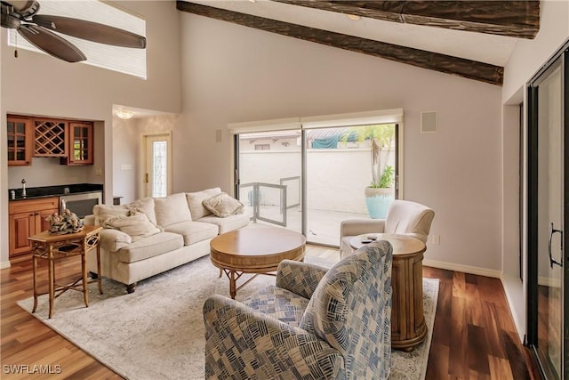 living area with light wood finished floors, baseboards, indoor wet bar, and beamed ceiling