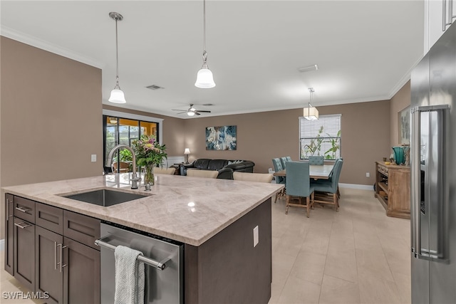 kitchen featuring pendant lighting, crown molding, stainless steel appliances, a sink, and light stone countertops