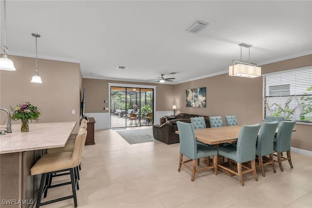 dining area featuring visible vents, ornamental molding, a ceiling fan, and wainscoting