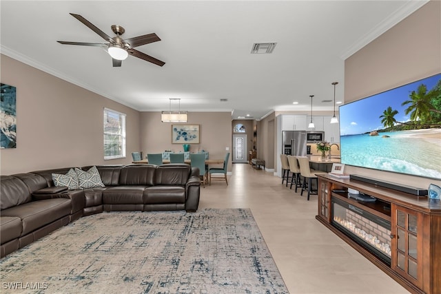 living area featuring ornamental molding, visible vents, and a ceiling fan