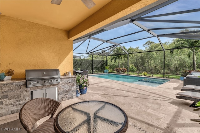 outdoor pool with glass enclosure, a patio area, a grill, and an outdoor kitchen