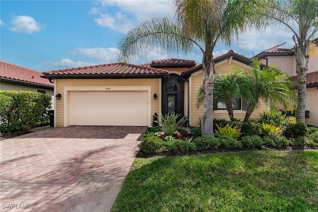 mediterranean / spanish house with a garage, a tile roof, and decorative driveway