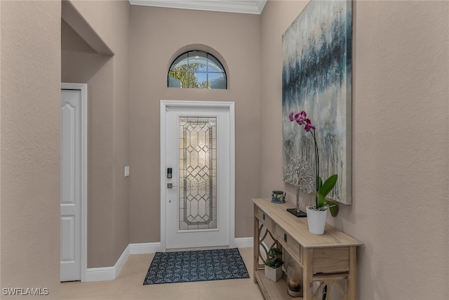 tiled entrance foyer featuring baseboards and crown molding