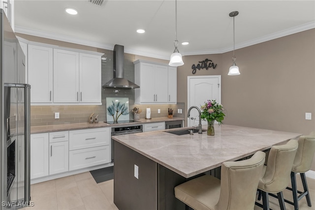 kitchen with white cabinets, stainless steel appliances, crown molding, wall chimney range hood, and a sink