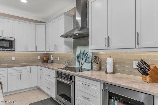 kitchen featuring wine cooler, stainless steel appliances, white cabinetry, wall chimney exhaust hood, and crown molding