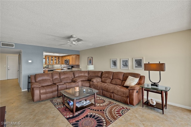 living room featuring a ceiling fan, visible vents, a textured ceiling, and light tile patterned floors