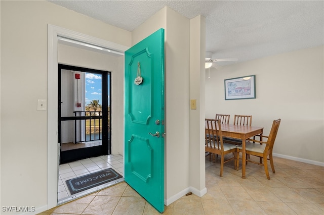 tiled foyer with ceiling fan, baseboards, and a textured ceiling