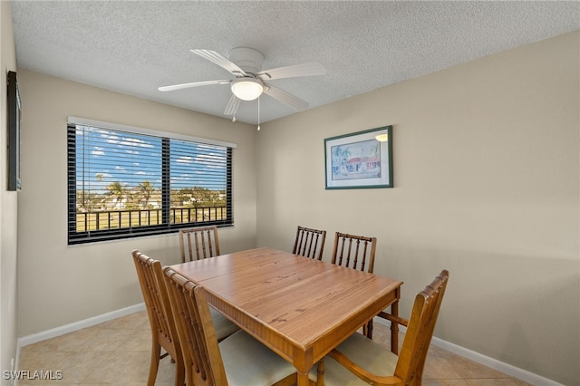 dining area with light tile patterned floors, baseboards, a ceiling fan, and a textured ceiling