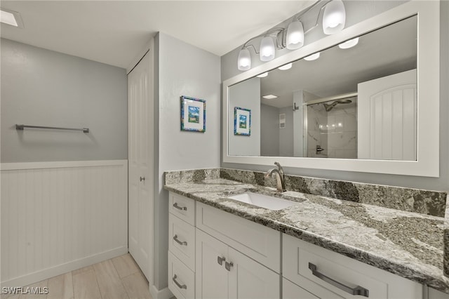 full bath with a wainscoted wall, a shower stall, and vanity