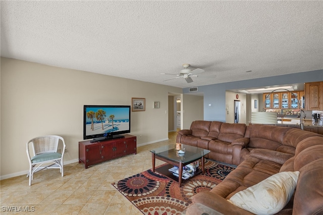 living room with a textured ceiling, visible vents, a ceiling fan, and light tile patterned flooring