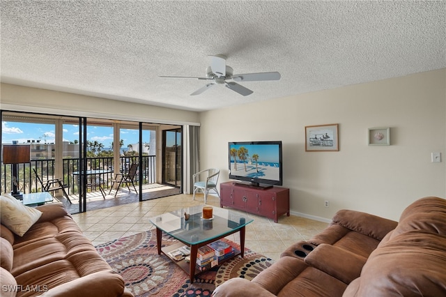 living area featuring light tile patterned floors, ceiling fan, baseboards, and a textured ceiling