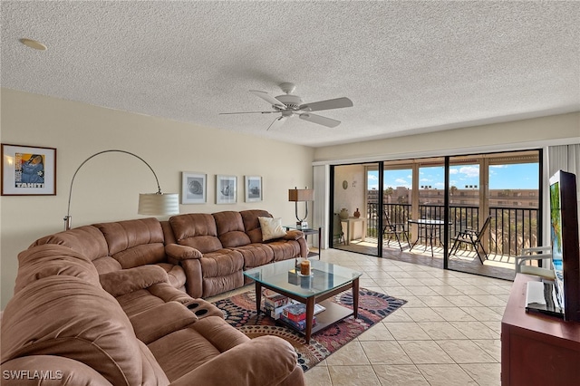 living area with a ceiling fan, light tile patterned flooring, and a textured ceiling