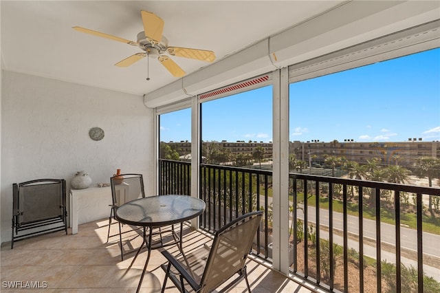 sunroom / solarium featuring ceiling fan and a city view