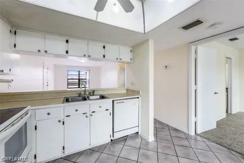 kitchen with light countertops, visible vents, white cabinetry, a sink, and white appliances