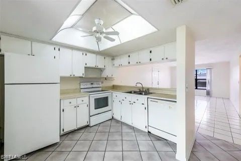 kitchen with white appliances, light tile patterned floors, ceiling fan, light countertops, and a sink