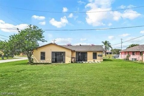 back of property with a yard and stucco siding