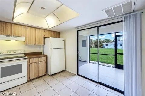 kitchen featuring dark countertops, visible vents, light tile patterned flooring, white appliances, and under cabinet range hood