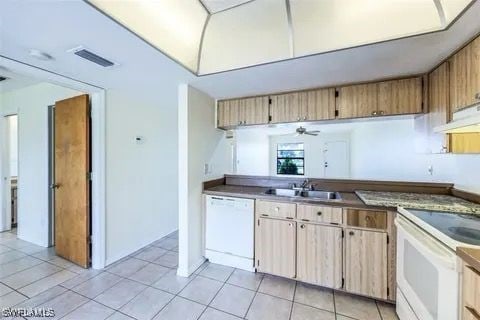 kitchen featuring light tile patterned flooring, under cabinet range hood, white appliances, a sink, and visible vents