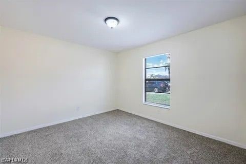 carpeted empty room featuring baseboards