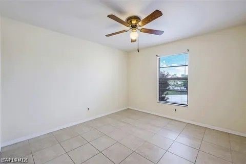 spare room with ceiling fan, light tile patterned floors, and baseboards