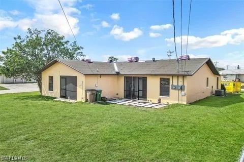 back of house featuring central air condition unit, a lawn, and stucco siding