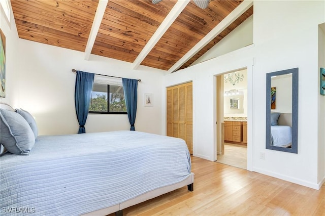 bedroom with beamed ceiling, connected bathroom, wood ceiling, and light wood-style floors